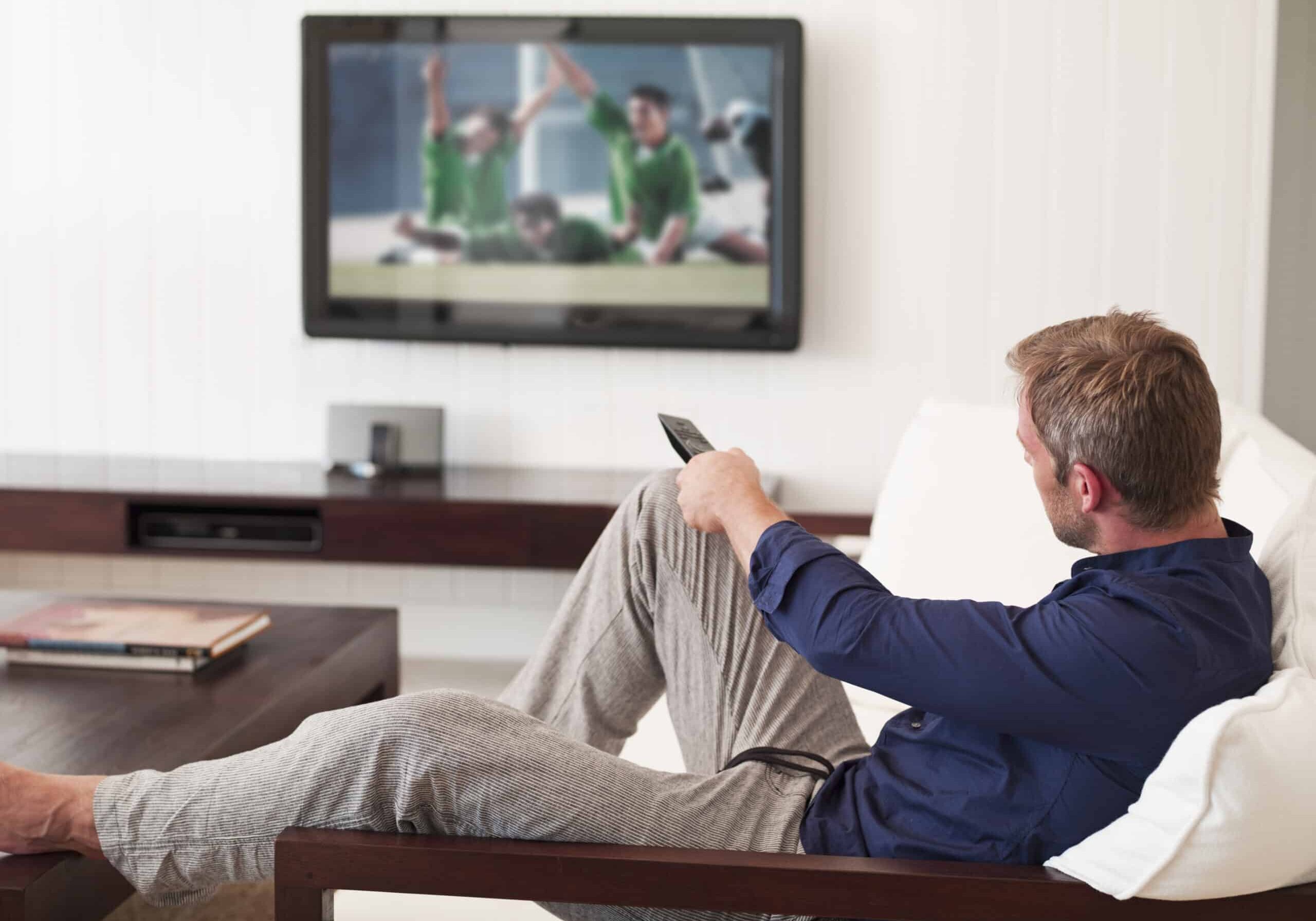 Man changing TV channels with remote control